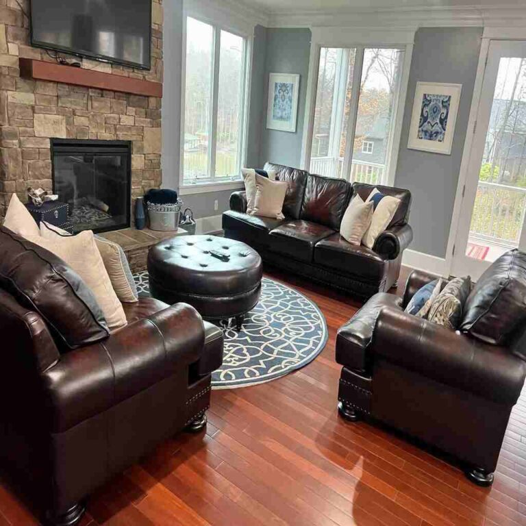 Immaculate living room with polished hardwood floors, spotless leather furniture, crystal-clear windows, and dust-free stone fireplace demonstrating premium home cleaning services in Charlotte and Raleigh NC